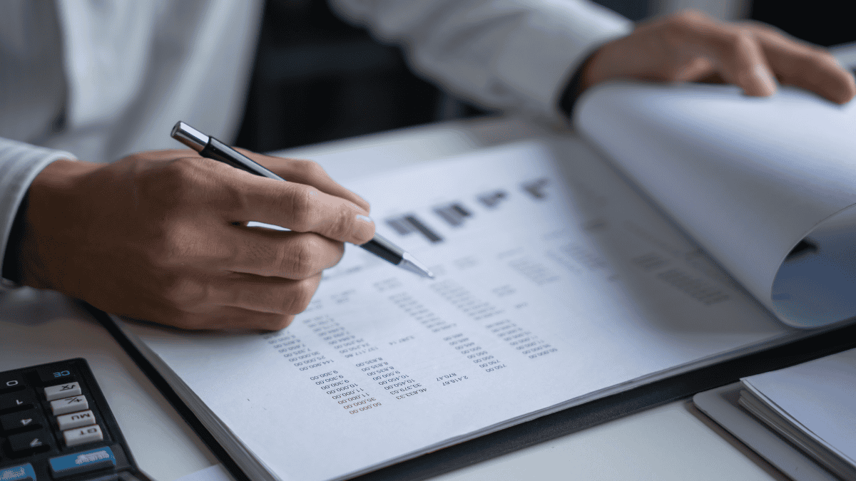 Attorney reviewing law firm trust account financial records and reconciliation reports with a pen and calculator