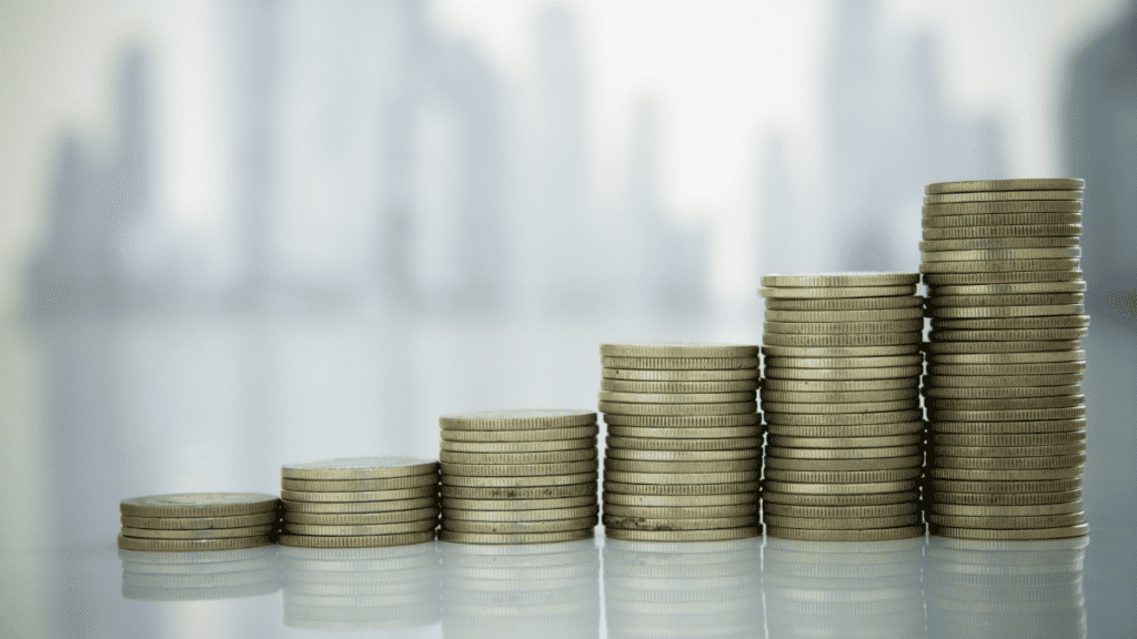 Stacked coins increasing in height against a blurred city skyline, representing steady law firm cash flow growth