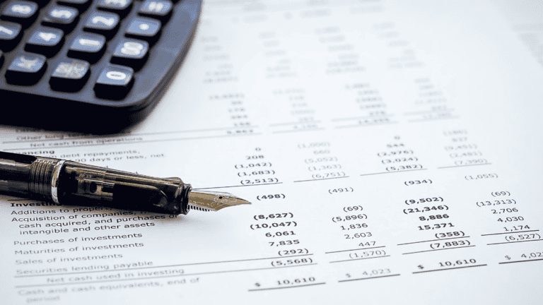 Fountain pen resting on a financial report showing detailed line-item figures, with a calculator nearby, representing the close review behind law firm financial KPIs